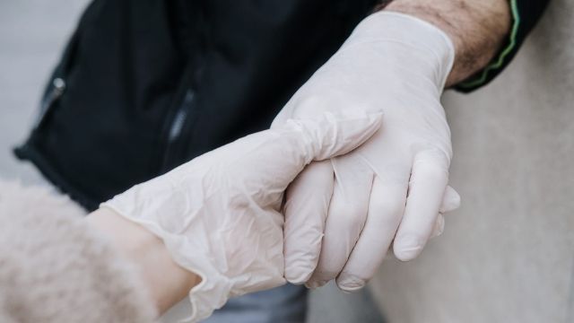 Two recovering addicts holding hands to show support while wearing rubber gloves