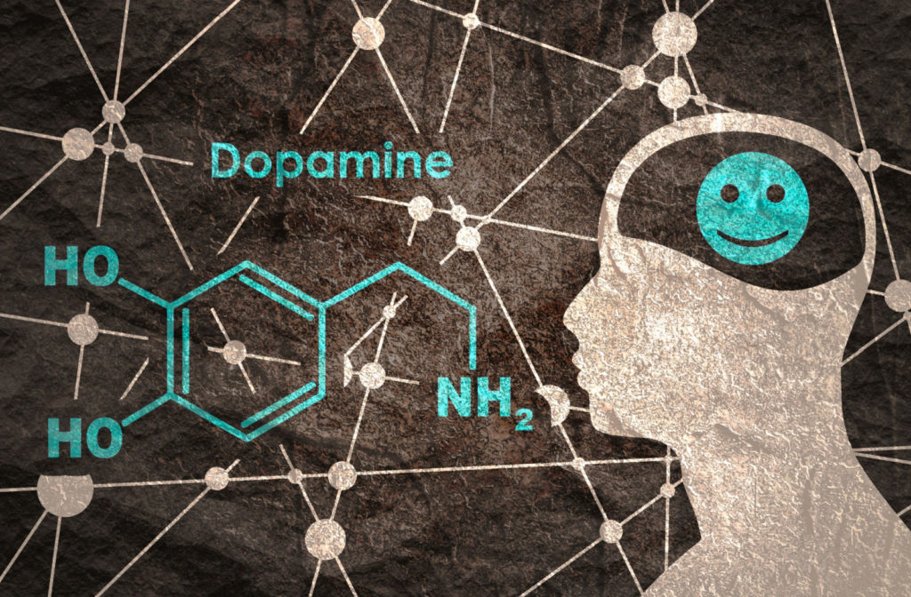 A sketch of the chemical structure of dopamine and a silhouette of a head with a smiley face where the brain is