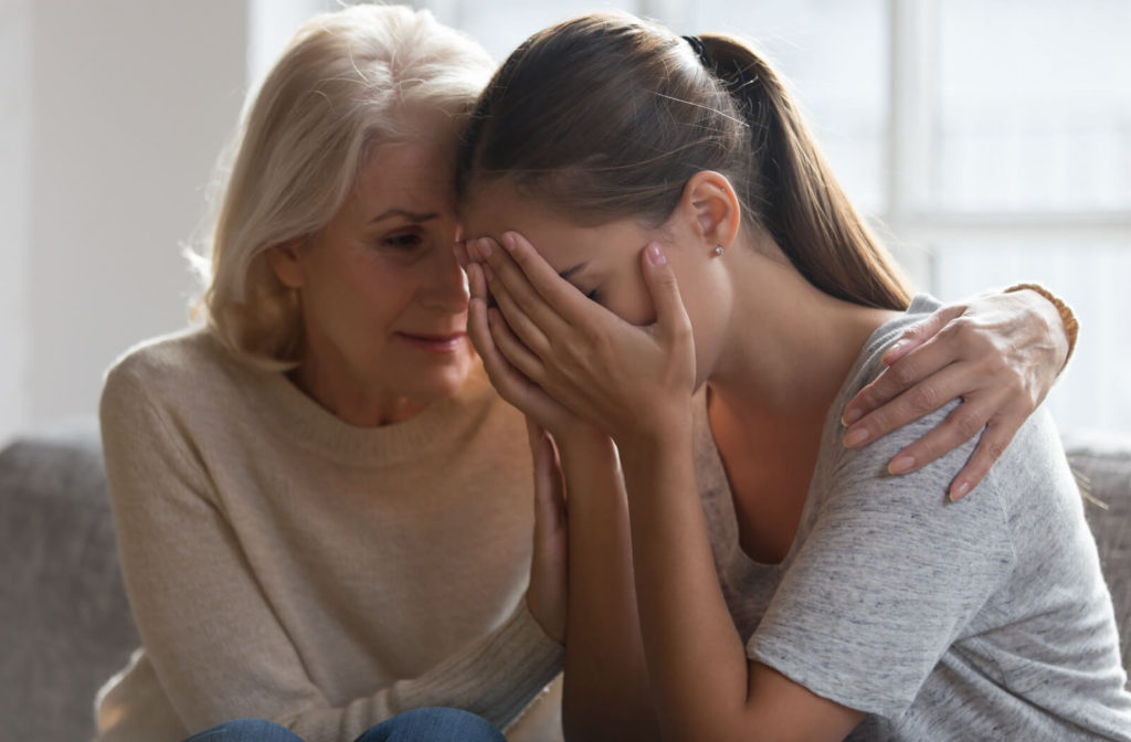A young woman reunited with her mother after addiction recovery,  A young woman is crying and being comforted by her mother.