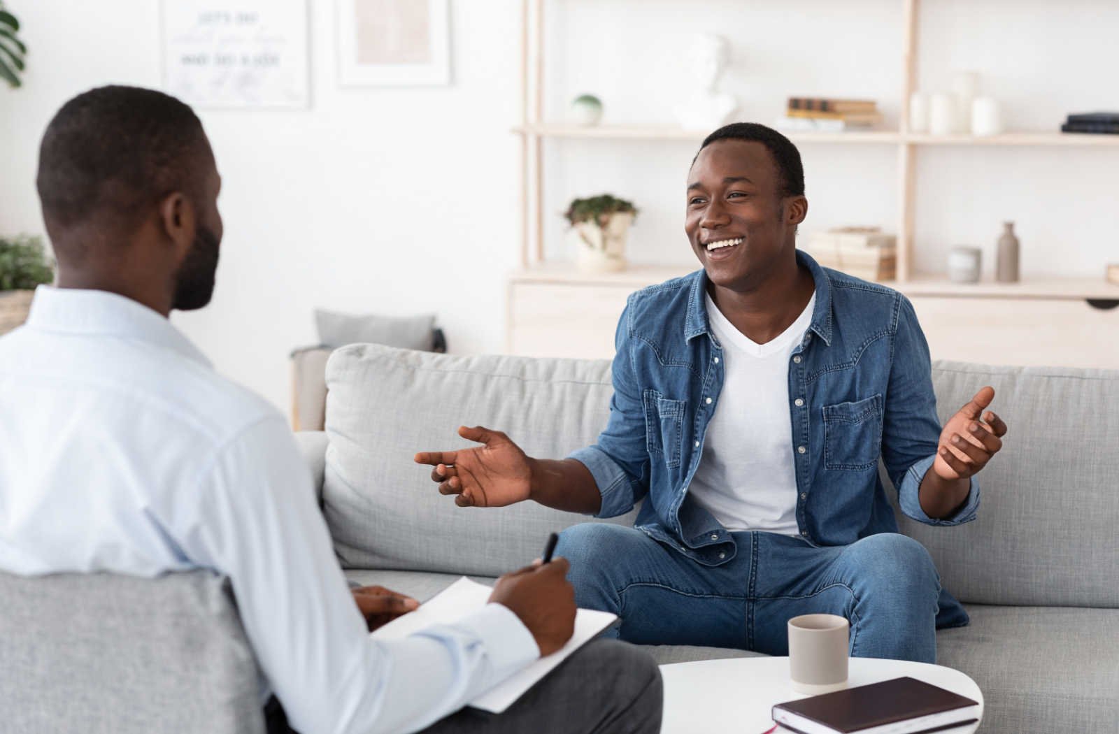 A cheerful young man talking to a male psychologist during a successful counselling session.