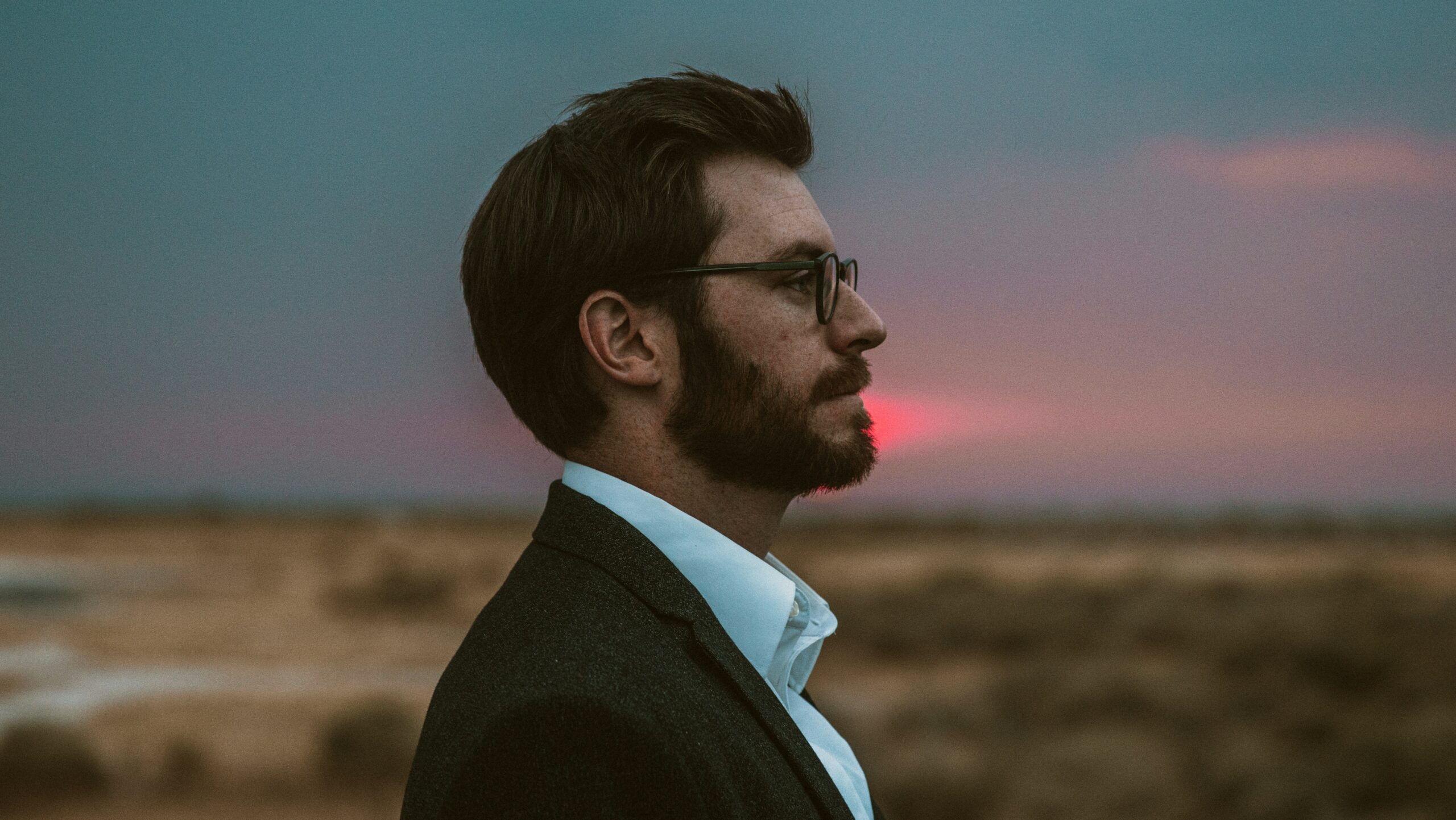 Man in suit in field looking in the distance