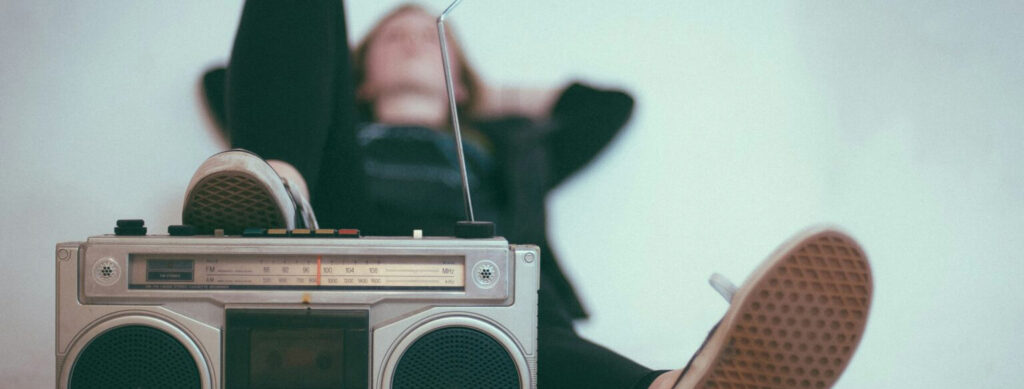 Young adult lays back listening to radio, with a radio in the foreground